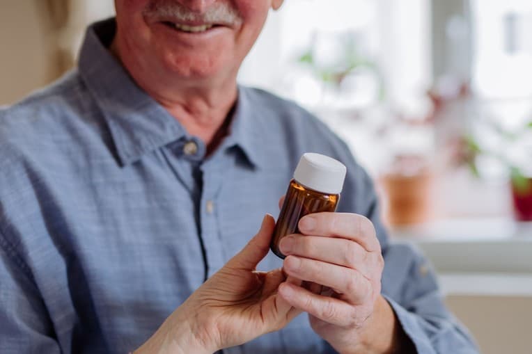 a senior man holding a bottle containing medication