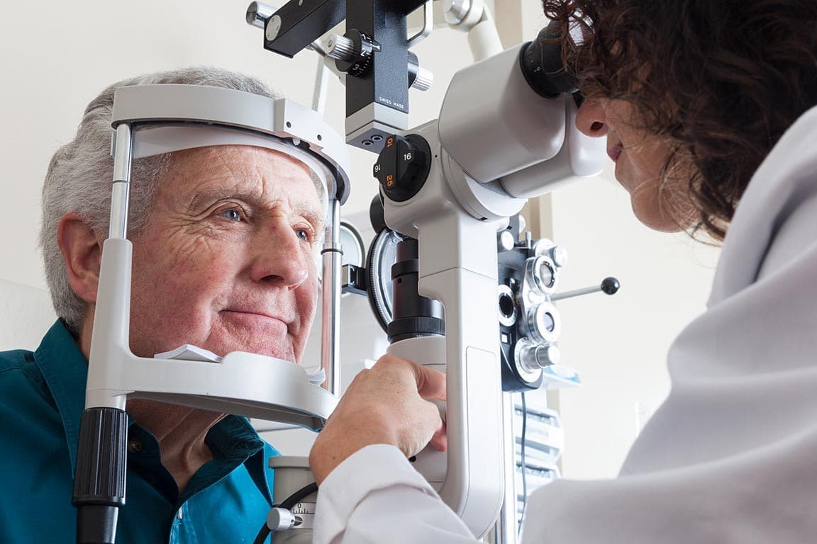 A woman optometrist is examining the eyes of an elderly man
